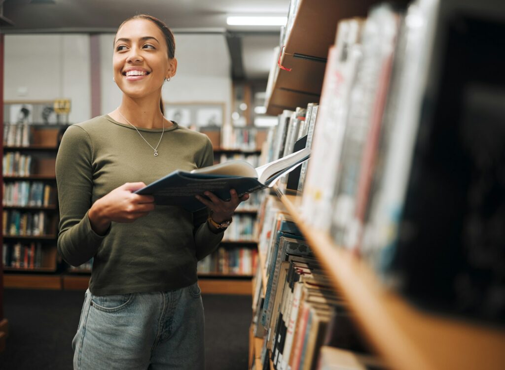 Student, happy and reading books in library for education learning or university research in bookst