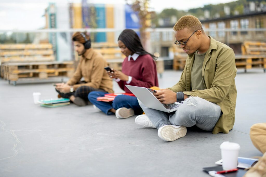 Students sitting and using smartphones on asphalt
